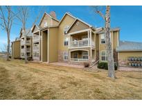 Condominium featuring dual balconies with a stone facade and tan siding at 6021 W Castlegate Dr # E18, Castle Rock, CO 80108