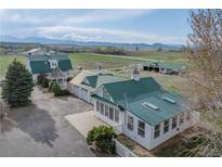 Picturesque farm with white buildings, gazebo, green metal roofs, and mountain views in the background at 6231 Prospect Rd, Longmont, CO 80503