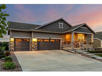 Charming two-story home featuring a two-car garage and welcoming front porch with stone accents at 27375 E Alder Dr, Aurora, CO 80016