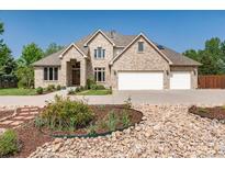 Beautiful tan brick home with a three car garage and a well manicured front yard and flower beds at 4245 S Dawson St, Aurora, CO 80014