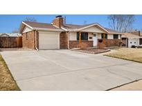 Charming brick home featuring an attached garage and a spacious concrete driveway for ample parking space at 1667 S Balsam Ct, Lakewood, CO 80232