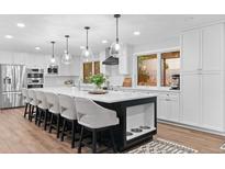 Bright kitchen with white cabinetry, stainless steel appliances, and a large island with bar seating at 9939 E Aberdeen Ave, Englewood, CO 80111