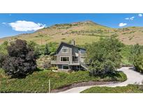 Charming grey two-story home boasts professional landscaping and a mountain view backdrop at 14150 Foothill Ln, Golden, CO 80401
