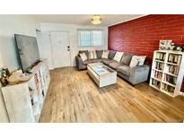 Inviting living room features a comfortable sectional sofa, red brick accent wall, and bright natural light at 6800 E Tennessee Ave # 351, Denver, CO 80224