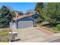 Charming two-story home features a large driveway, attached two-car garage, manicured lawn, and mature trees at 8679 Apache Plume Dr, Parker, CO 80134