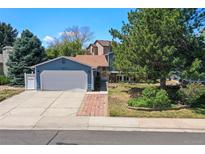 Charming blue two-story home features a well-manicured lawn, brick walkway, and an attached two-car garage at 8679 Apache Plume Dr, Parker, CO 80134