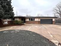Ranch style home with a large driveway and two-car garage, complimented with fresh landscaping at 6586 W Leawood Dr, Littleton, CO 80123