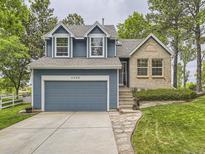 Charming two-story home featuring a blue exterior, brick accent, mature trees, and a well-manicured front yard at 11523 Sandy Creek Ln, Parker, CO 80138