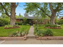Charming home featuring a landscaped front yard with mature trees and a welcoming walkway at 4580 S Huron St, Englewood, CO 80110