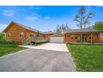Charming single-Gathering home featuring a log cabin exterior, deck, well-manicured lawn, and a two-car garage at 1415 Isabell St, Golden, CO 80401