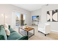 Bright living room featuring a modern sofa, stylish coffee table, and sliding glass doors to the outside at 10052 W Ute Pl # 202, Littleton, CO 80127