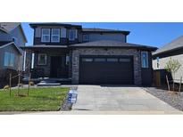 Two story home with stylish dark gray trim, stone accents, and well-manicured lawn at 6040 Keyser Pl, Brighton, CO 80601
