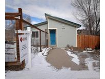 Gray house with teal door, snow on ground, wooden fence, and real estate sign at 26259 Kingsbury Rd, Kittredge, CO 80457