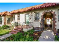 Charming home featuring a red tile roof, arched entrance, and well-maintained front yard with flower beds at 1422 Ivy St, Denver, CO 80220