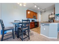 Eat-in kitchen boasts wood cabinetry and updated appliances, with dining area table and chairs at 2682 S Cathay Way # 307, Aurora, CO 80013