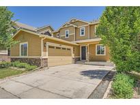 Tan two-story home featuring a two-car garage and charming stone accents at 6612 S Muscadine Ct, Aurora, CO 80016