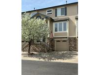 Charming townhome featuring a stone facade, attached garage and beautiful flowering tree at 11328 W Radcliffe Dr, Littleton, CO 80127