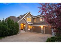 Beautiful two-story home with a stone archway, three car garage, and meticulously maintained landscaping at 7284 Timbercrest Ln, Castle Pines, CO 80108