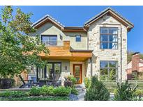 Two-story home with stone and wood accents, a balcony, and a landscaped front yard at 1237 S Saint Paul St, Denver, CO 80210