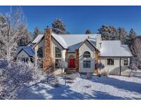 Stunning home with stone chimney, snow-covered roof, and bright red door in a picturesque winter setting at 2880 Lake Meadow Dr, Monument, CO 80132