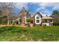Charming stone accents highlight this two-story home with lush lawn and mature trees at 2880 Lake Meadow Dr, Monument, CO 80132