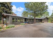 Charming single-story home with a paved driveway, mature trees, and beautifully landscaped front yard at 29663 Paint Brush Dr, Evergreen, CO 80439