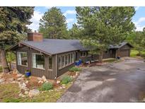 Charming home with a sunroom, a paved driveway, and beautifully landscaped with flower pots and rock features at 29663 Paint Brush Dr, Evergreen, CO 80439