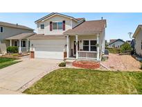 Charming two-story home features a manicured lawn, an attached two-car garage, and a covered front porch at 9579 Bighorn Way, Littleton, CO 80125