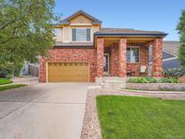 Charming two-story brick home featuring a well-manicured lawn and inviting front porch at 21220 E Nassau Ave, Aurora, CO 80013