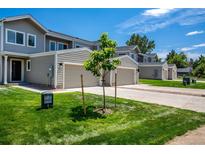 View of townhomes with attached garages and well-maintained lawns on a sunny day at 5242 Columbine Ln, Denver, CO 80221