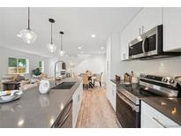 Well-lit kitchen featuring stainless steel appliances, island with sink, and adjacent dining area at 5242 Columbine Ln, Denver, CO 80221