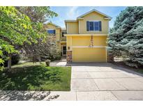 Charming two-story home featuring a well-maintained lawn, mature trees and a welcoming facade at 5338 Potentilla St, Brighton, CO 80601