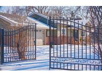 Ranch style home with brick facade, gated entrance, and snowy yard at 1150 W Caley Ave, Littleton, CO 80120