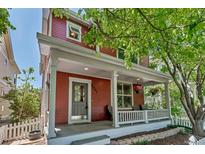 Charming red two-story home with a welcoming front porch and beautifully landscaped yard at 2737 Ulster St, Denver, CO 80238