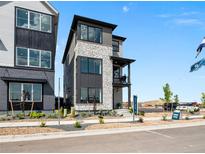 Modern three-story home showcasing stone and dark siding against a blue sky at 1787 W 166Th Ave, Broomfield, CO 80023