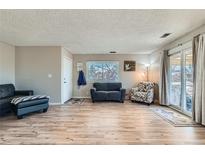 Bright living room featuring wood floors, neutral walls, sliding glass door, and comfortable seating at 9943 Croke Dr, Denver, CO 80260