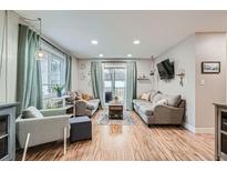 Bright living room with hardwood floors, comfy sofas, and sliding glass door to patio at 5995 E Iliff Ave # 120, Denver, CO 80222