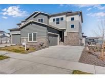 Modern two-story home featuring gray siding, stone accents, and a spacious driveway leading to an attached garage at 6863 Oak Canyon Cir, Castle Pines, CO 80108