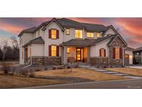Inviting two-story home featuring stone accents, a covered porch, and warm interior lighting at 15 Latigo Pl, Littleton, CO 80123
