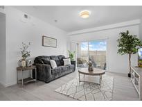 Bright living room featuring comfortable seating, stylish decor, and a sliding door to the balcony at 15700 E Jamison Dr # 8-208, Englewood, CO 80112