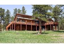 Inviting wood cabin with a spacious wrap-around deck nestled among mature trees at 13190 Coyote Song Trl, Conifer, CO 80433