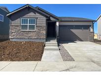 Charming one-story home featuring stone accents, a two-car garage, and a well-manicured front yard at 3911 N Shawnee St, Aurora, CO 80019