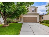 Charming two-story home featuring a manicured lawn, large tree and a spacious two-car garage at 2905 S Deframe Way, Lakewood, CO 80228