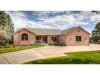 Charming brick home with a spacious driveway, well-maintained lawn, and inviting front porch at 1660 Old Antlers Way, Monument, CO 80132