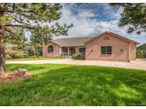 Charming brick home featuring a circular driveway and well-manicured lawn at 1660 Old Antlers Way, Monument, CO 80132