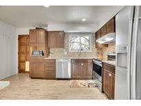 Well-lit kitchen featuring stainless steel appliances, tiled backsplash, and wood-look flooring at 16193 E Dickenson Pl, Aurora, CO 80013