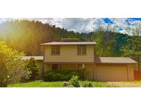 Charming two-story home featuring a well-maintained lawn and mature trees against a forested backdrop at 1037 Wagonwheel Gap Rd, Boulder, CO 80302