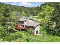 Stunning home exterior with a large deck surrounded by lush greenery and a serene mountain backdrop at 1037 Wagonwheel Gap Rd, Boulder, CO 80302