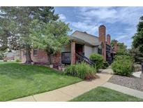 Inviting home featuring a brick exterior, charming front porch, and a well-maintained lawn with mature trees at 4231 S Fairplay Cir # A, Aurora, CO 80014