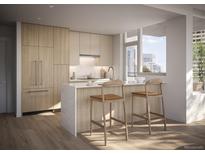 Modern kitchen featuring stainless steel appliances, light wood cabinets, and a breakfast bar with seating at 525 18Th St # 1207, Denver, CO 80202